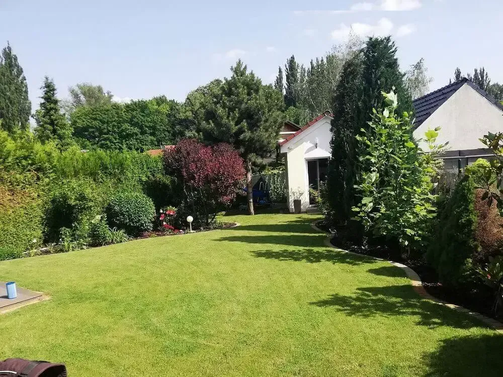 Záhrada s pokoseným trávnikom, plná zelene, stromov a okrasných drevín